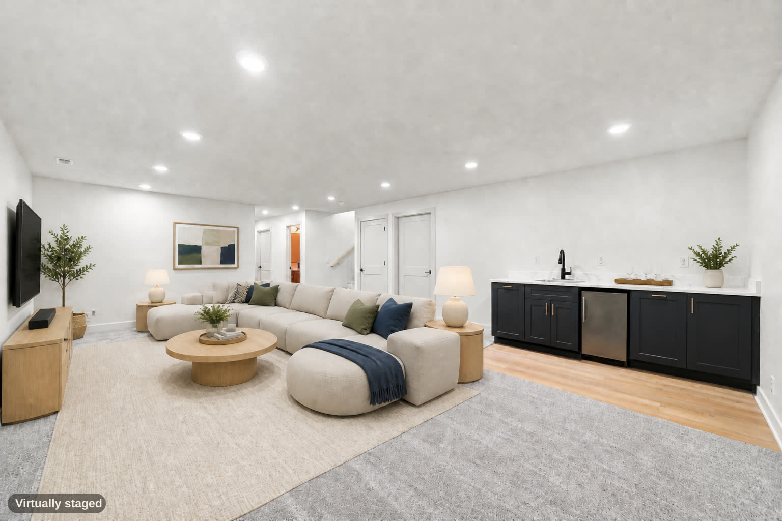 Same basement, virtually staged with a sectional, tables, and bar glassware.