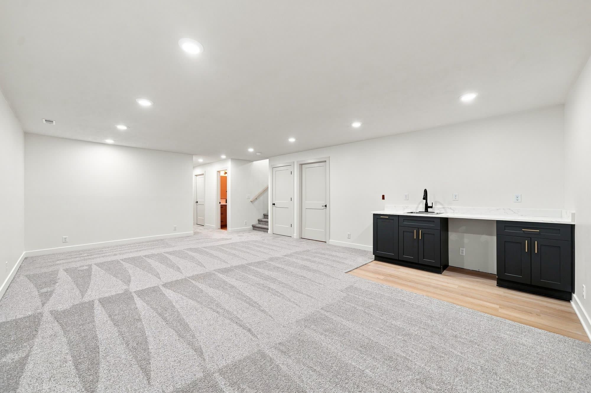 Finished empty basement with wet bar and no furniture.