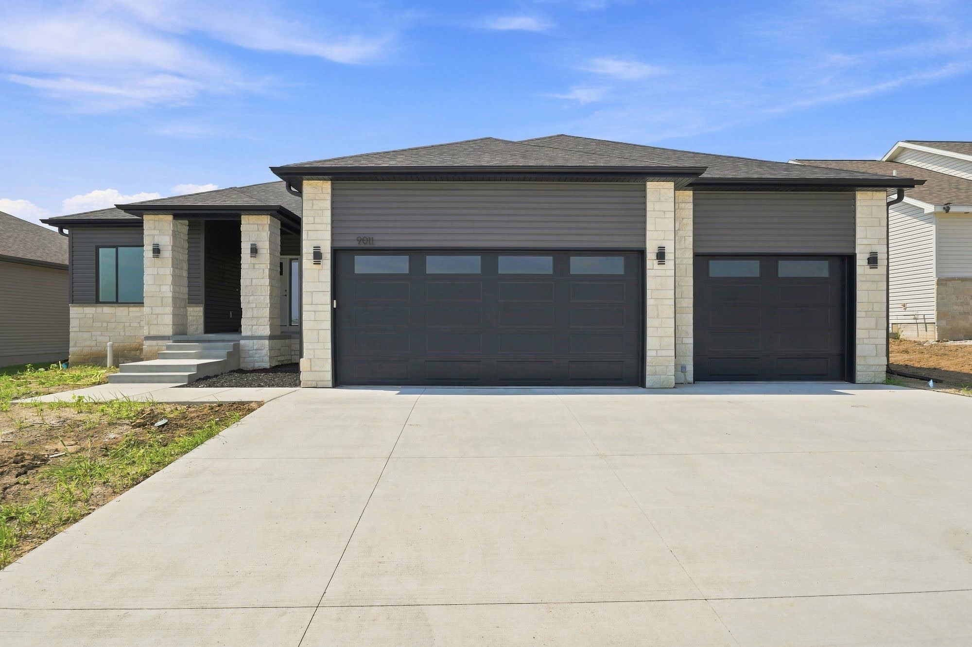 Front of a new-build house with garage and unfinished dirt yard.