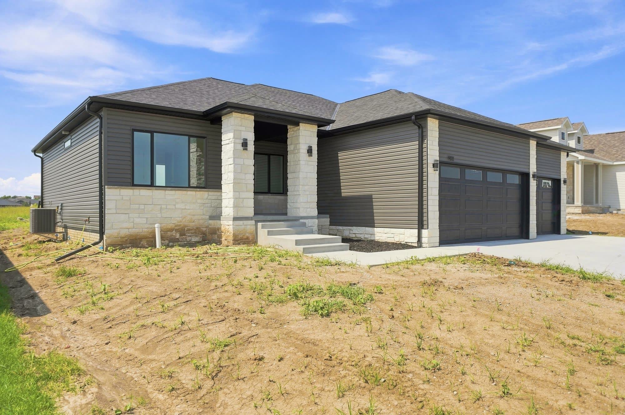 Side yard of a new-build house, unfinished dirt and weeds.